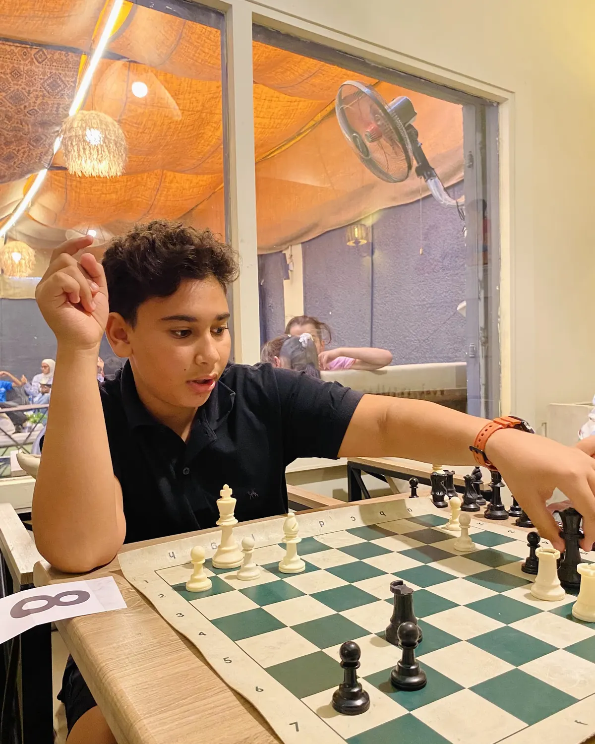 طفل بيفكر في نقلته التالية على رقعة الشطرنج مع مدرب Chess Your Child